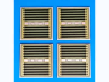 View 1: Four square AlN thick film heaters with dark serpentine resistance paths and terminal pads on a clean blue surface
