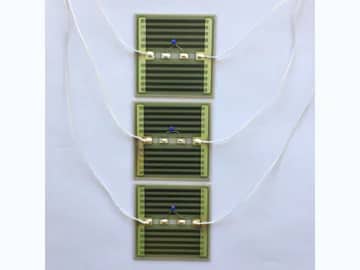 View 3: Three wired AlN thick film heater samples with printed tracks, soldered leads, and small sensing components