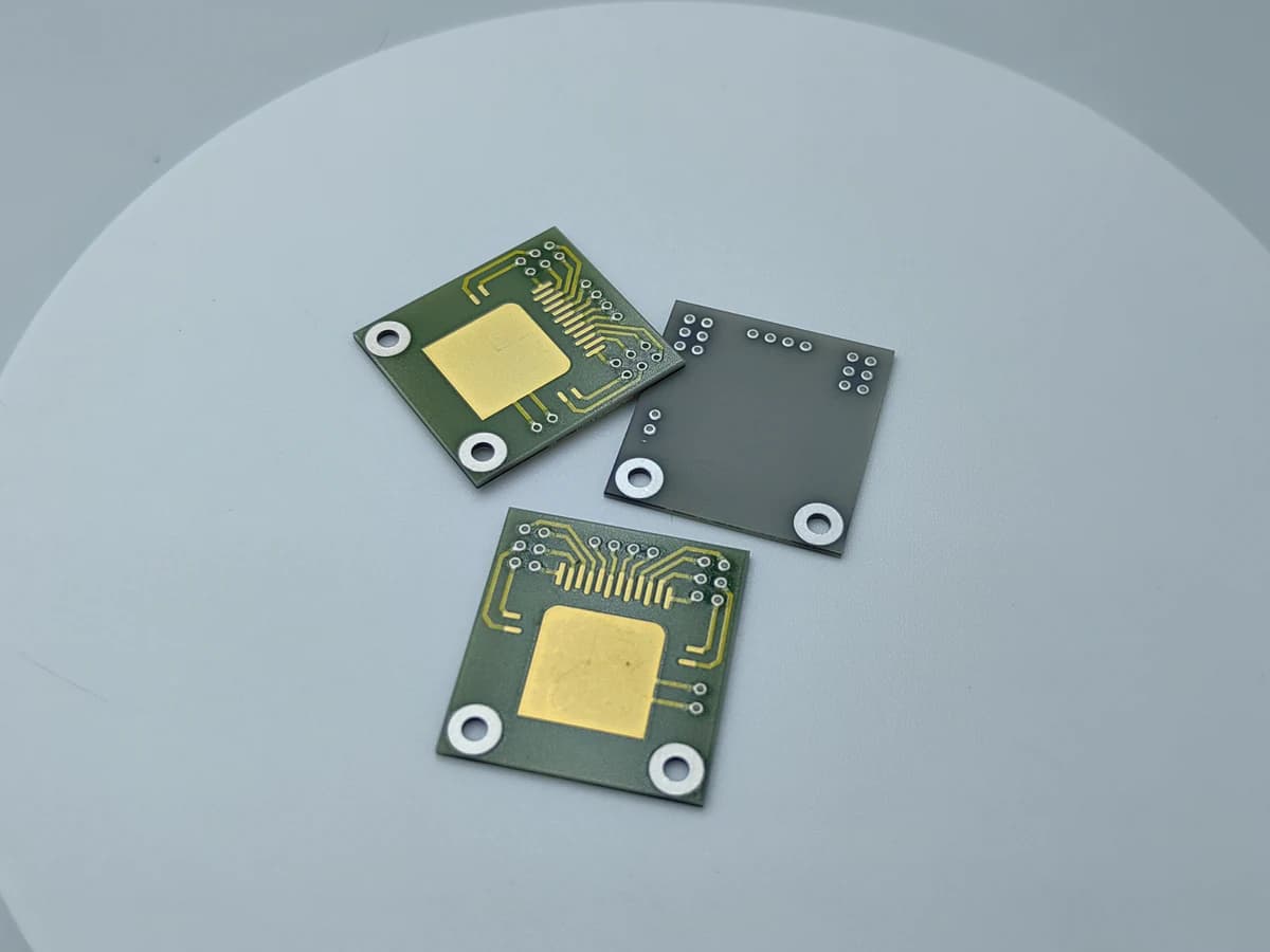 Real AlN circuit sample with visible gold-colored pads and routed conductor areas