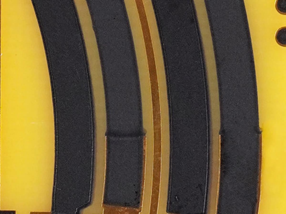 Source-derived macro view of black printed track texture and adjacent copper-colored conductor paths on the supplied board