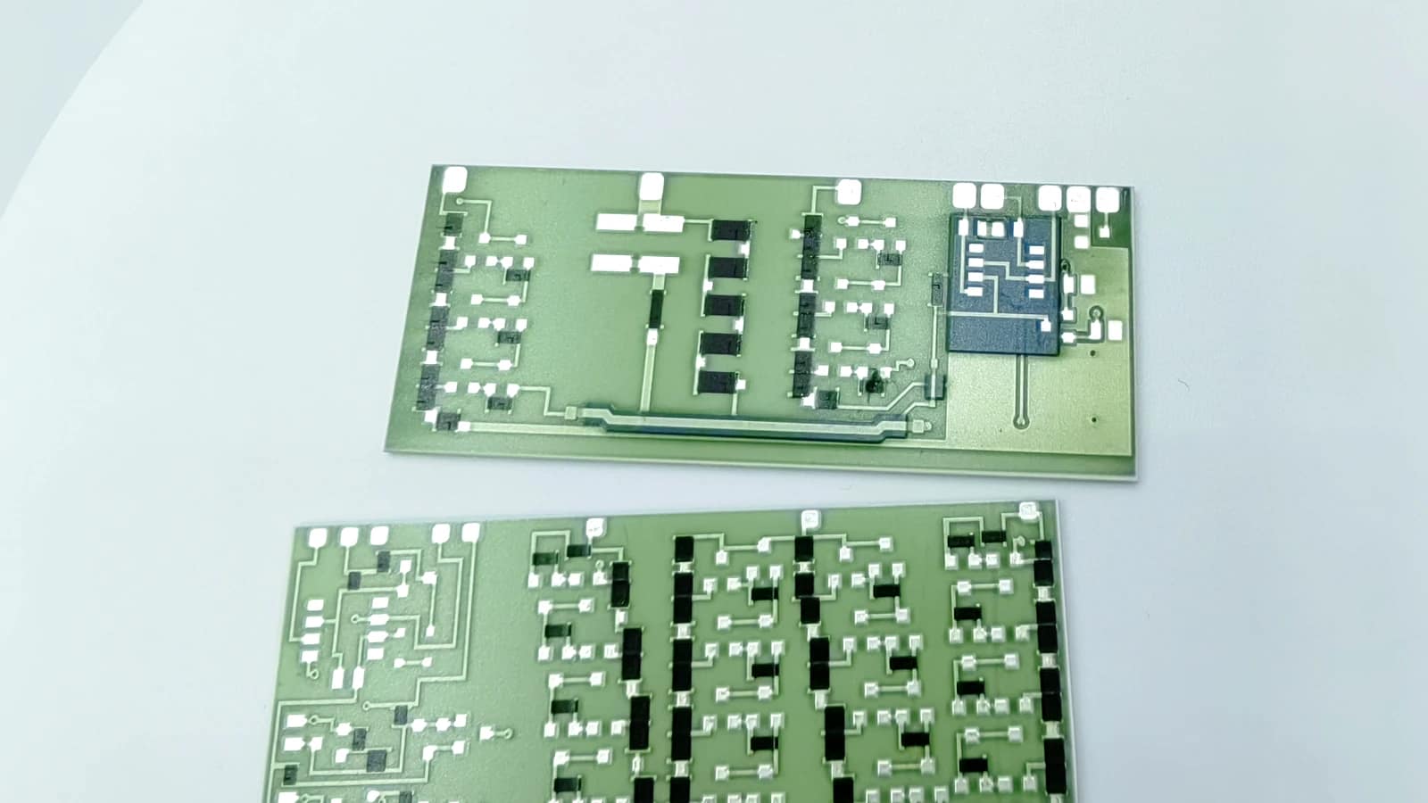 Real product photograph showing two rectangular circuit forms with different silver-colored routes, black blocks, and a localized blue area