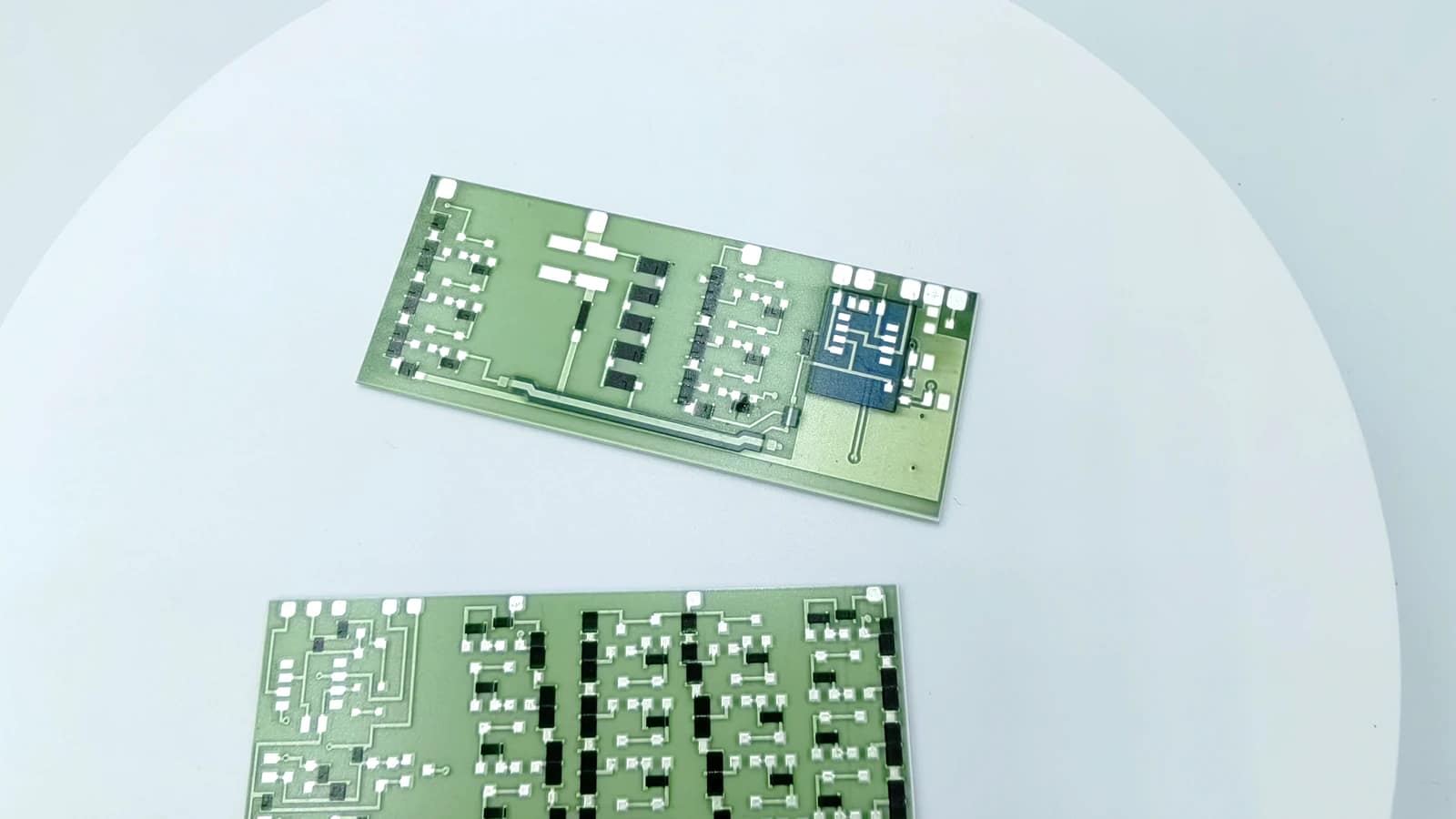 Real product photograph showing silver-colored routing, repeated black blocks, and rectangular green circuit forms