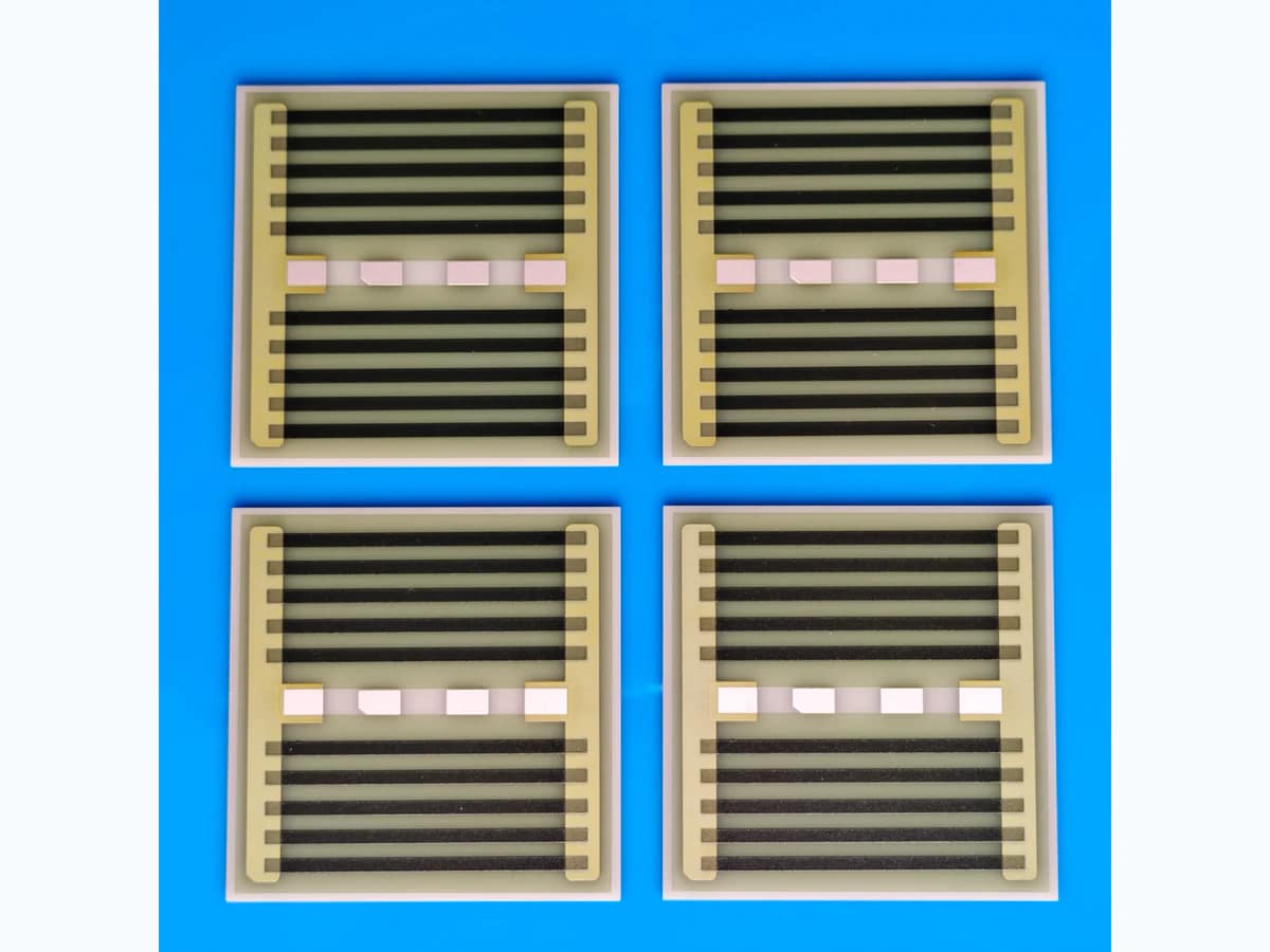 Four square AlN thick film heaters with dark serpentine resistance paths and terminal pads on a clean blue surface