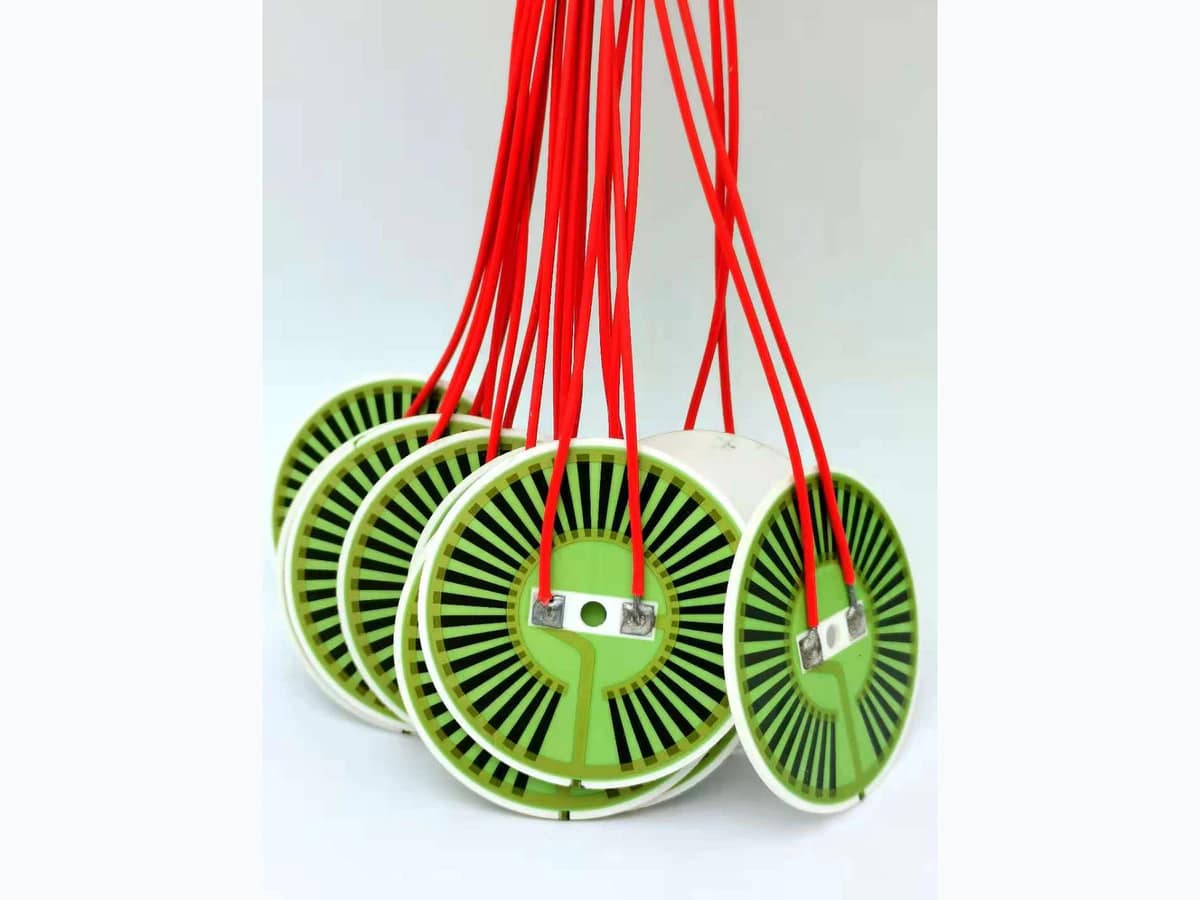 Round alumina heater discs showing white rims, visible printed patterns, terminals, and red leads