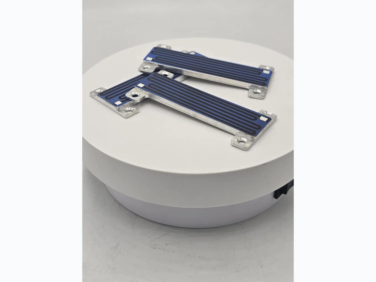Compact heater module showing a visible serpentine path, blue field, pads, and metal support