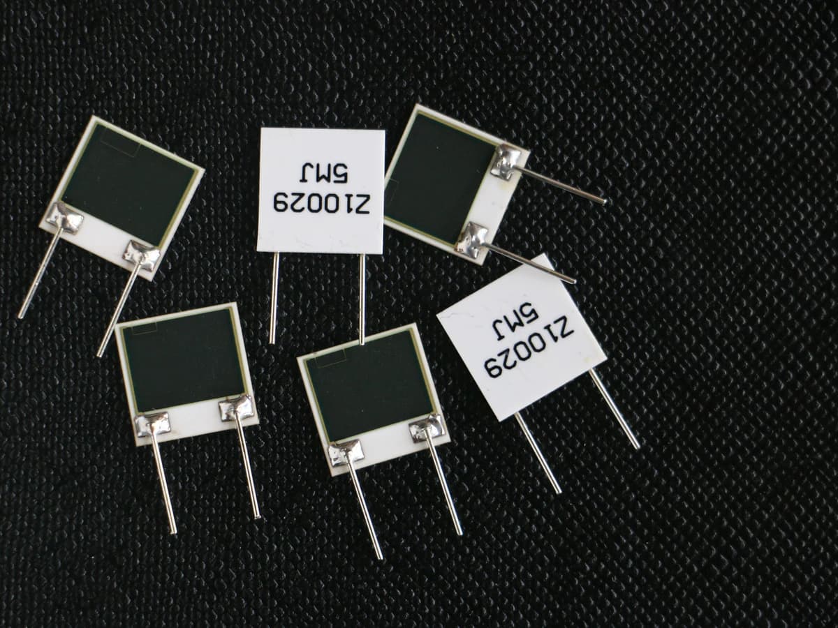 Real ceramic printed-resistor parts with soldered wire terminations and visible pad interfaces