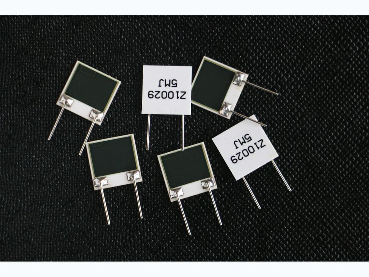 Ceramic two-terminal reference parts with dark surface regions, labels, leads, and metal terminals