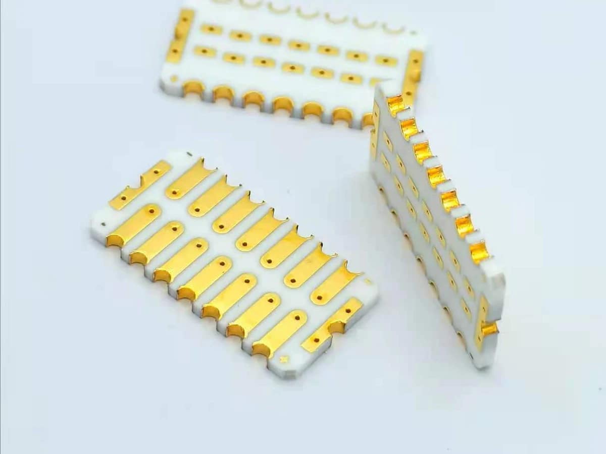 Controlled detail crop of a verified double-sided gold-colored ceramic PCB showing pads, rails, holes, and edge features