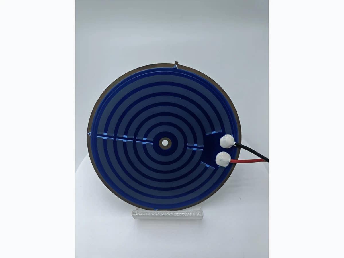 Supplied kettle heater photograph showing the first circular printed layout, terminal joints, red and black leads, and center feature