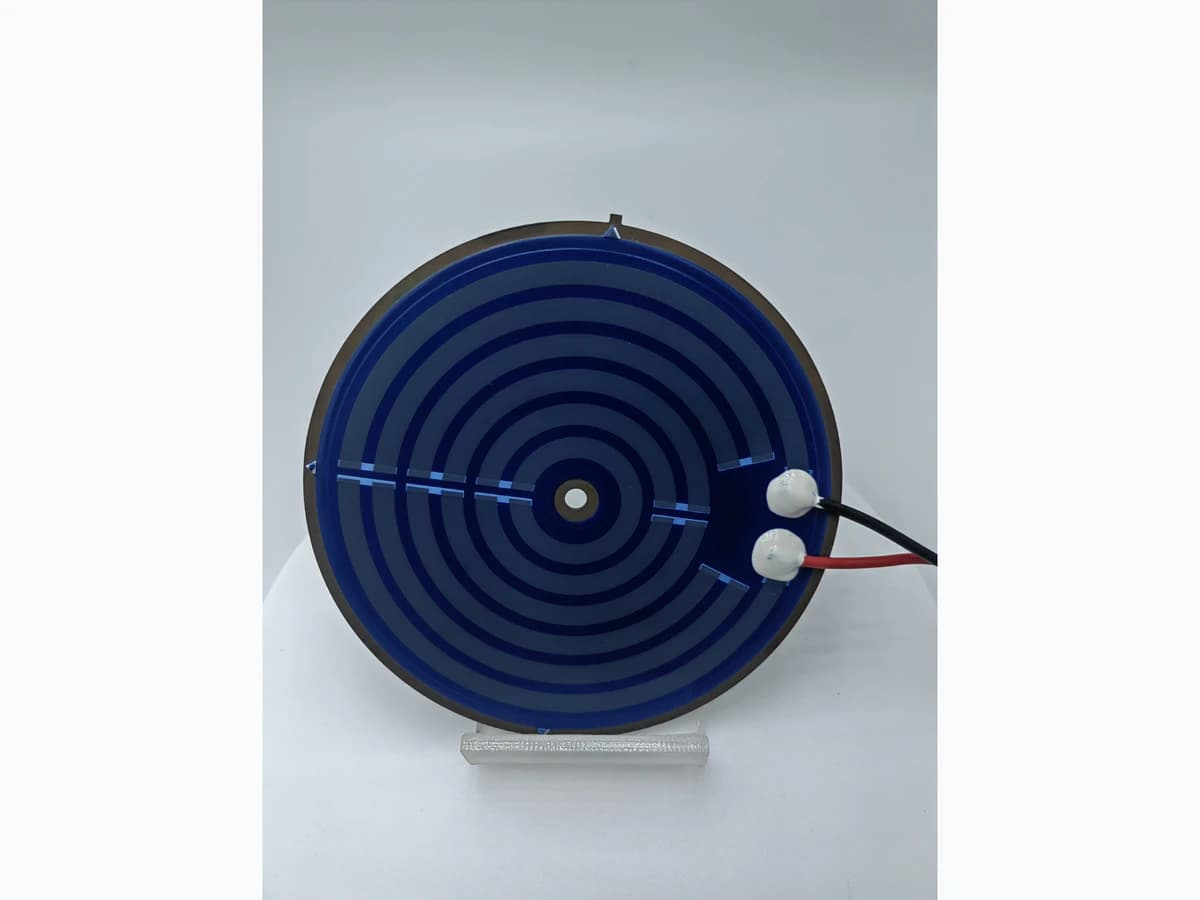 Close product photograph of a circular heater showing printed terminal pads and attached lead interfaces