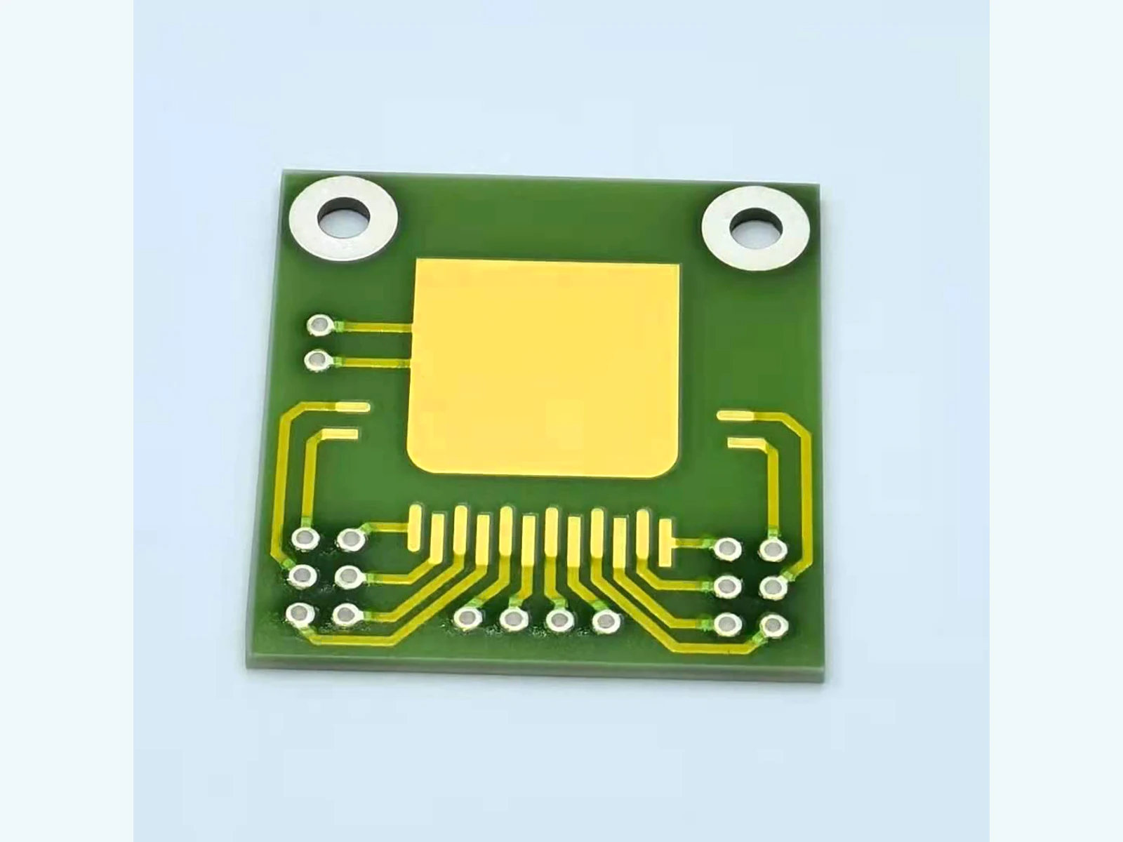 Front AlN thick film PCB view showing a large gold-colored pad, fine routing, openings, and rings