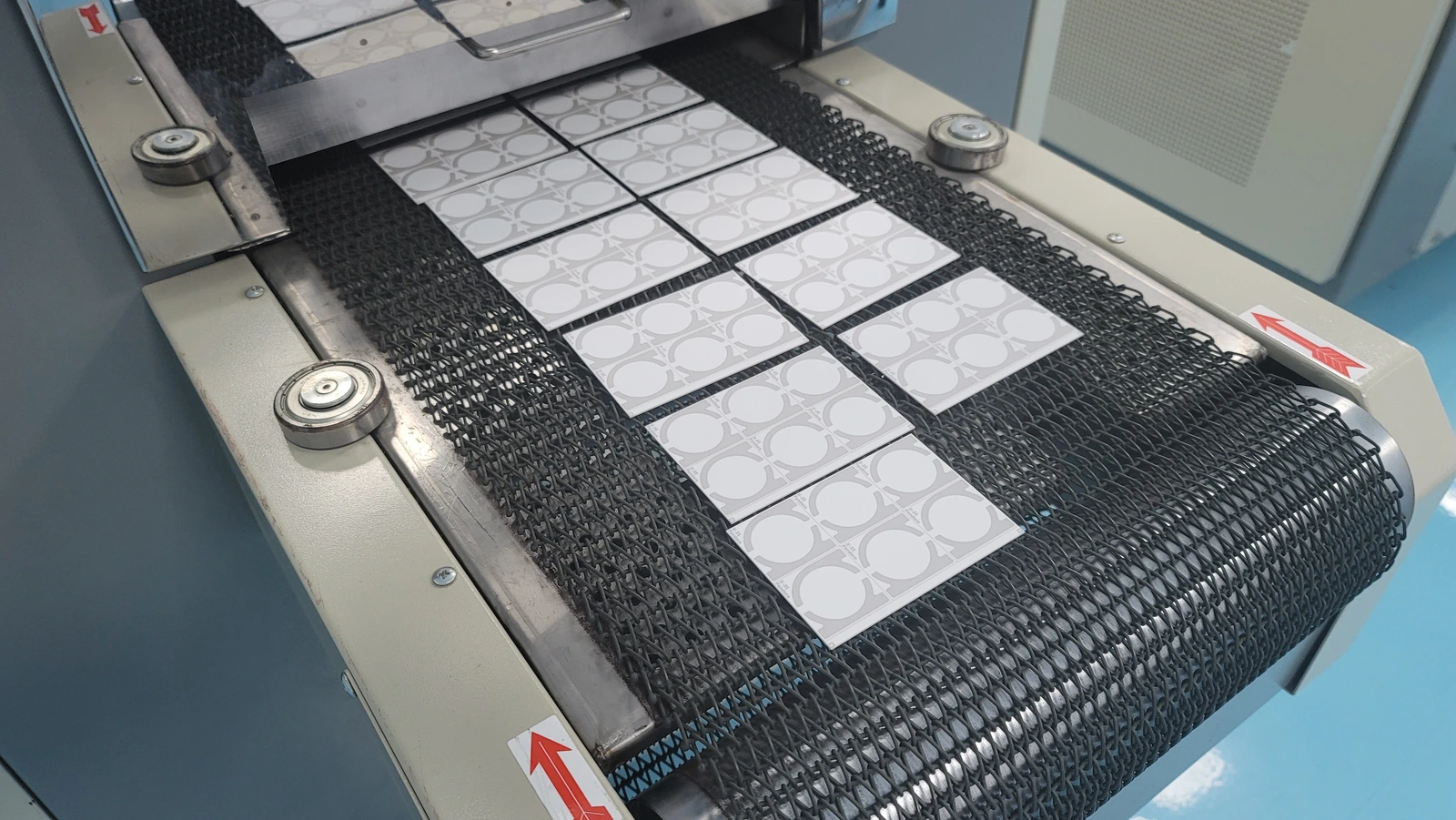 Ceramic circuit parts on a conveyor belt; every additional thermal pass belongs in the layer-stack process history.