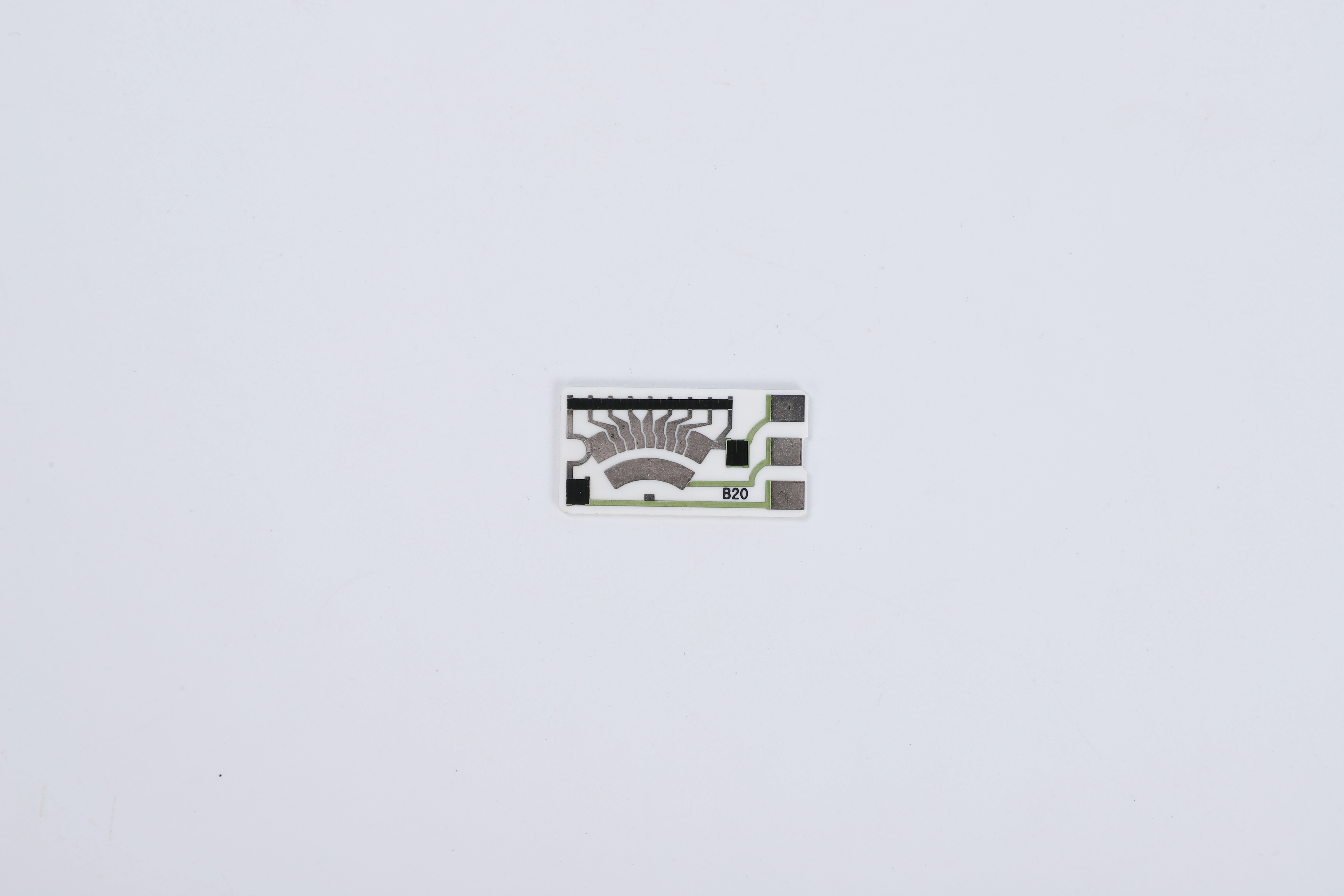 A ceramic resistive sensor card with nine segmented contact sectors, exposed terminal pads and green protected conductors.