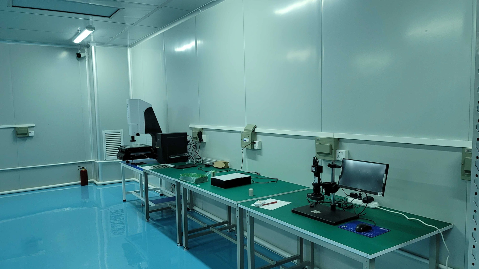 Optical inspection workstations with digital microscopes, specimen stages and ceramic parts on green workbenches.