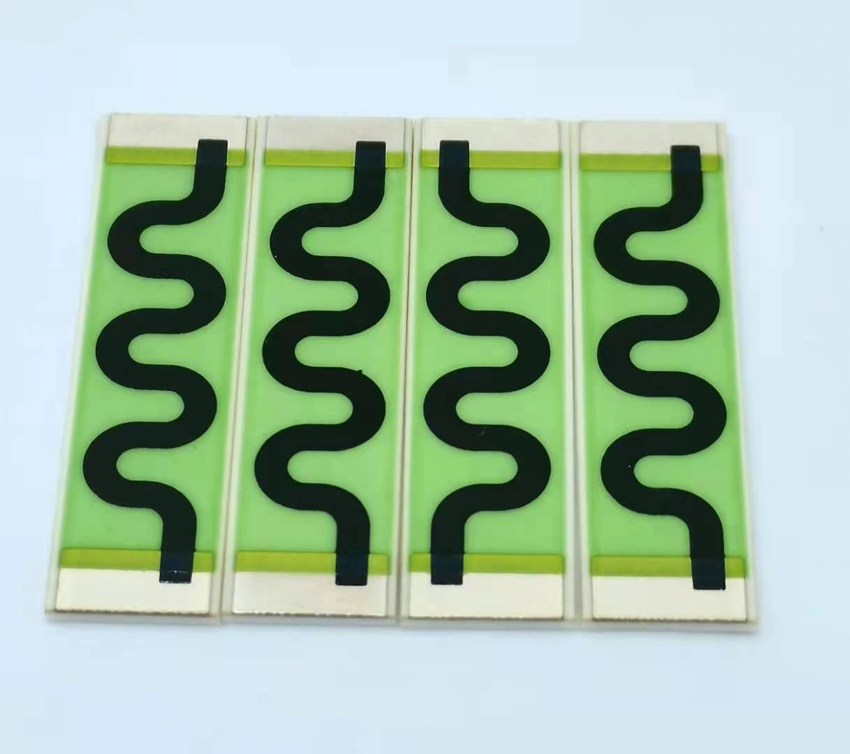Four rectangular ceramic resistors with green protective coverage, black serpentine paths and end terminations.