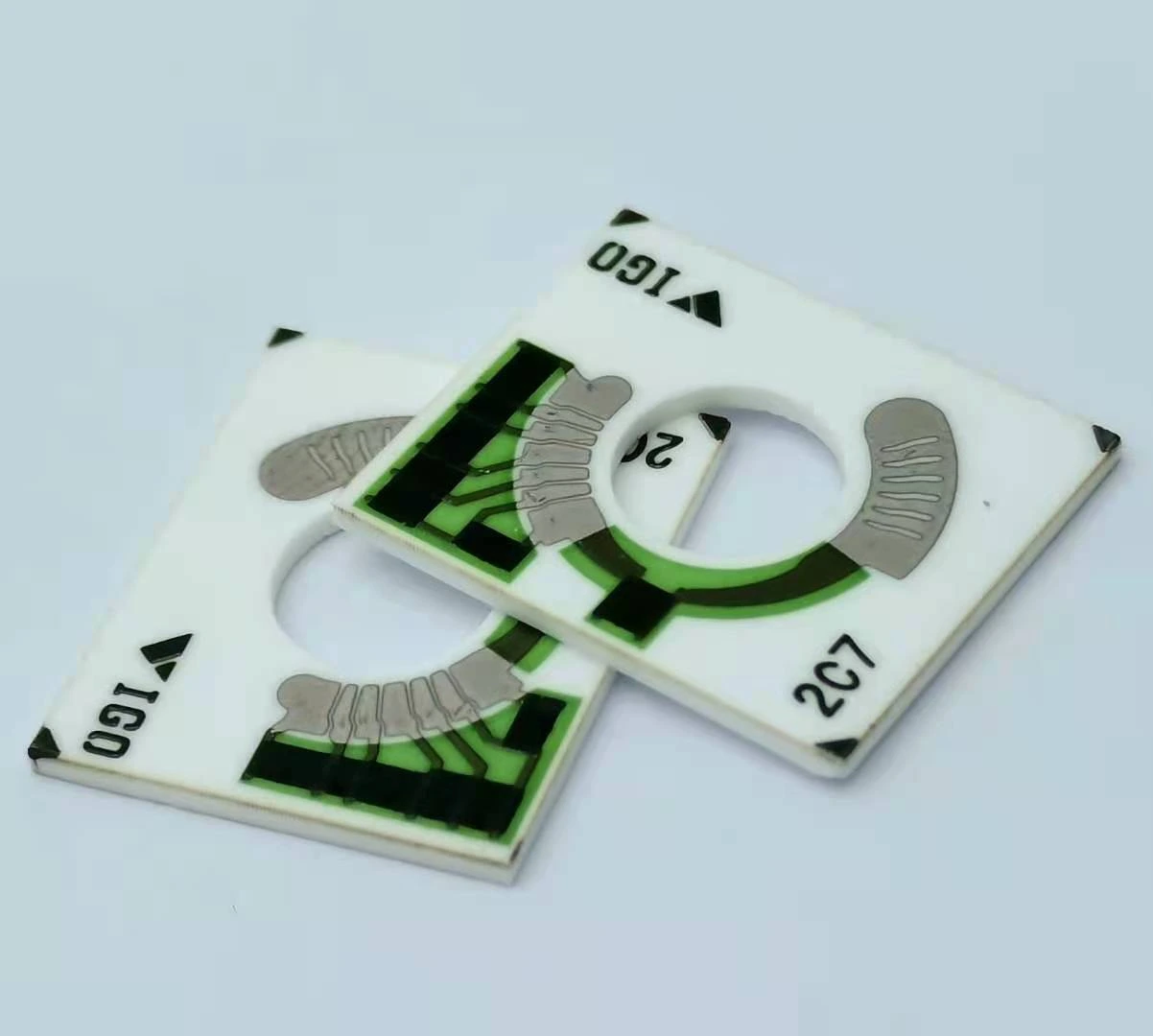 Two ceramic sensor cards with annular segmented tracks, central openings and green-protected conductor paths.