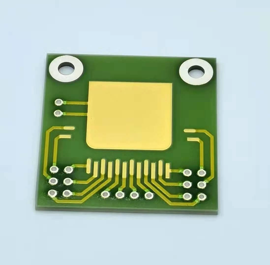 A ceramic circuit with a large gold-coloured attachment pad, a row of smaller contacts and two mounting apertures.