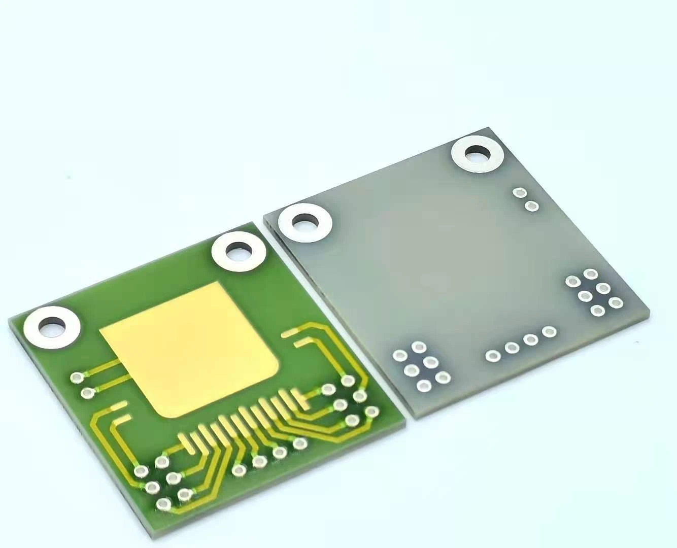 Front and reverse faces of a ceramic circuit with gold-coloured attachment pads, rows of contacts and mounting holes.