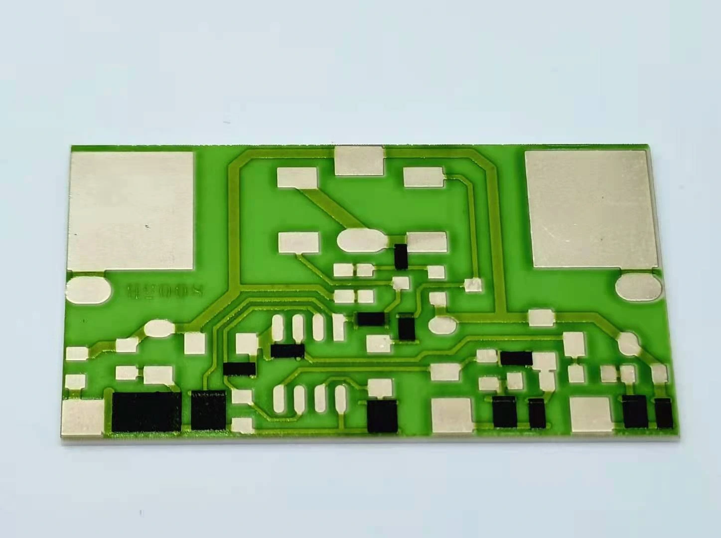 A green-glazed ceramic circuit with black resistor features, fine conductor paths and exposed metal pads.