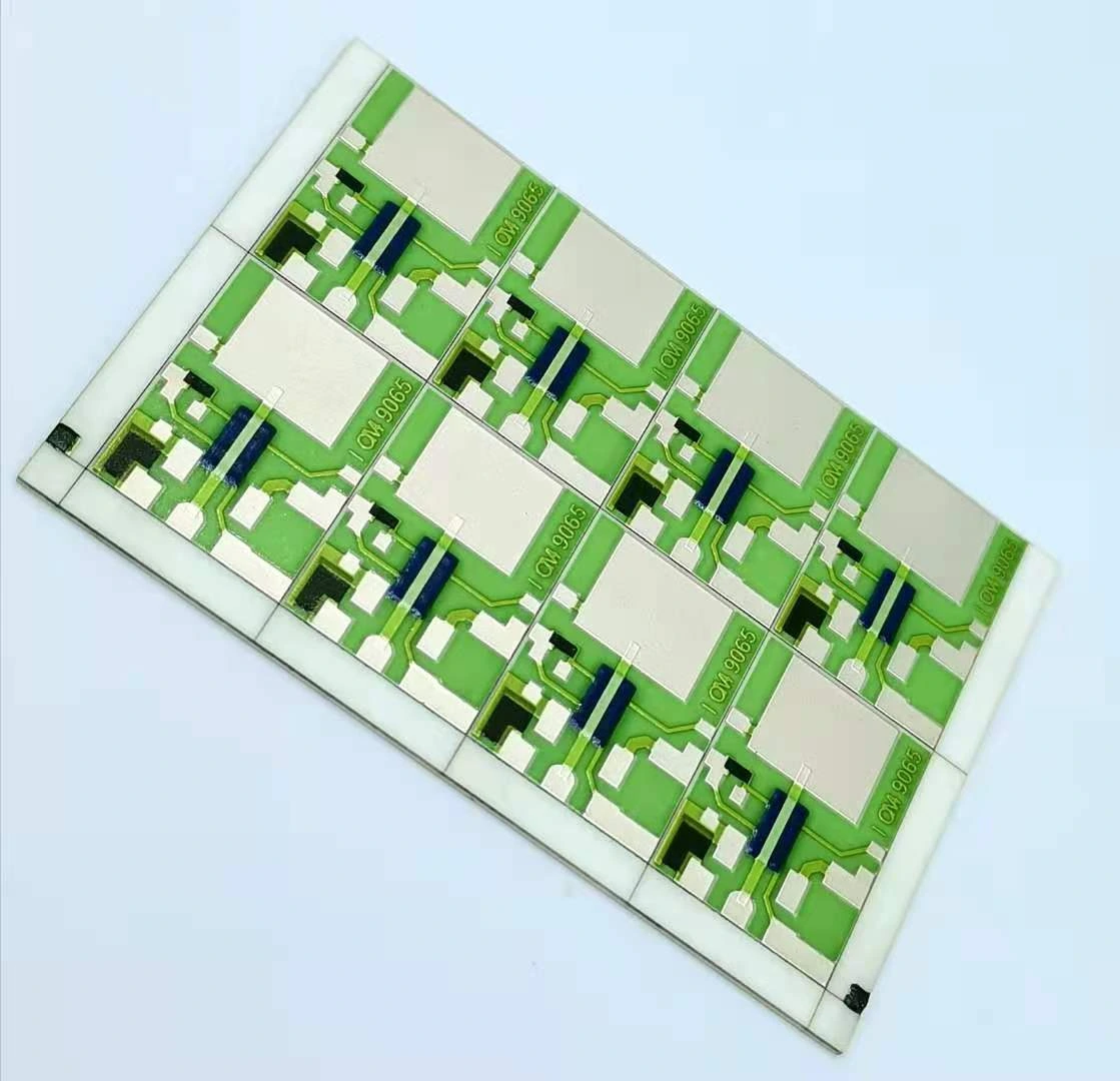 An oblique view of a ceramic circuit panel with green protective glass, black resistor features and repeated exposed pads.