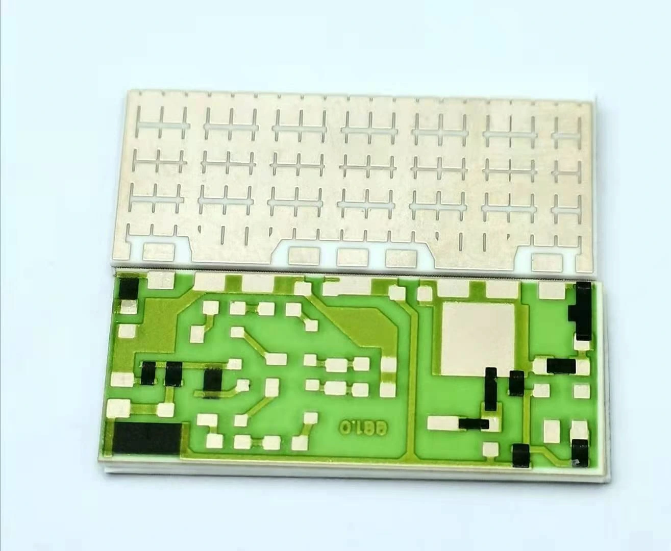 Front and reverse faces of a ceramic circuit, showing green-protected patterned routing and exposed metal areas.