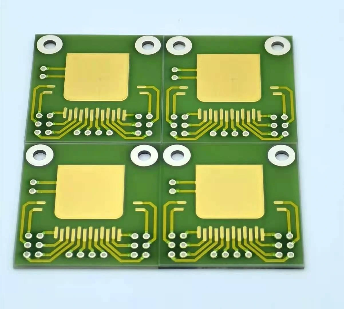 Four ceramic circuit units on a panel, with round mounting holes and exposed gold-coloured connection pads.