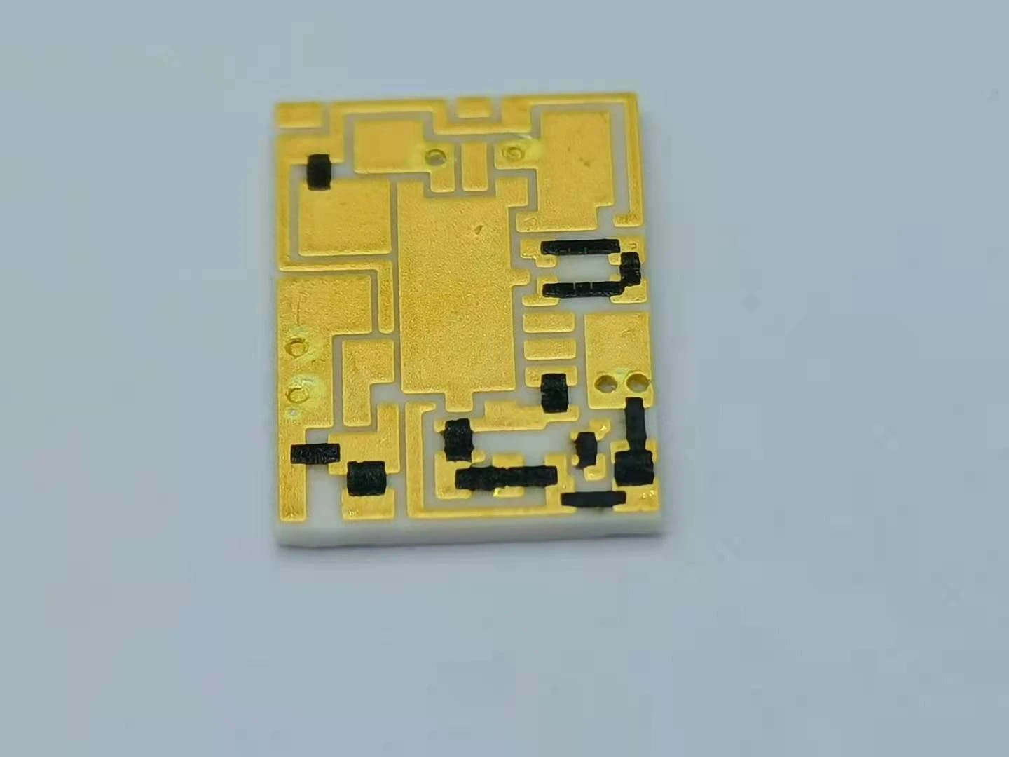 A printed circuit with gold-coloured conductors, exposed attachment areas and black resistor features.
