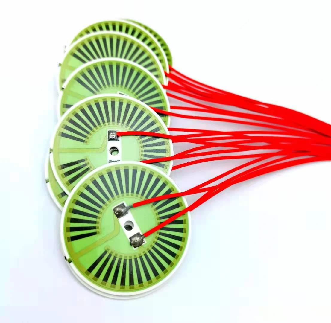 Round green-protected heater elements with radial resistive paths and attached red leads.