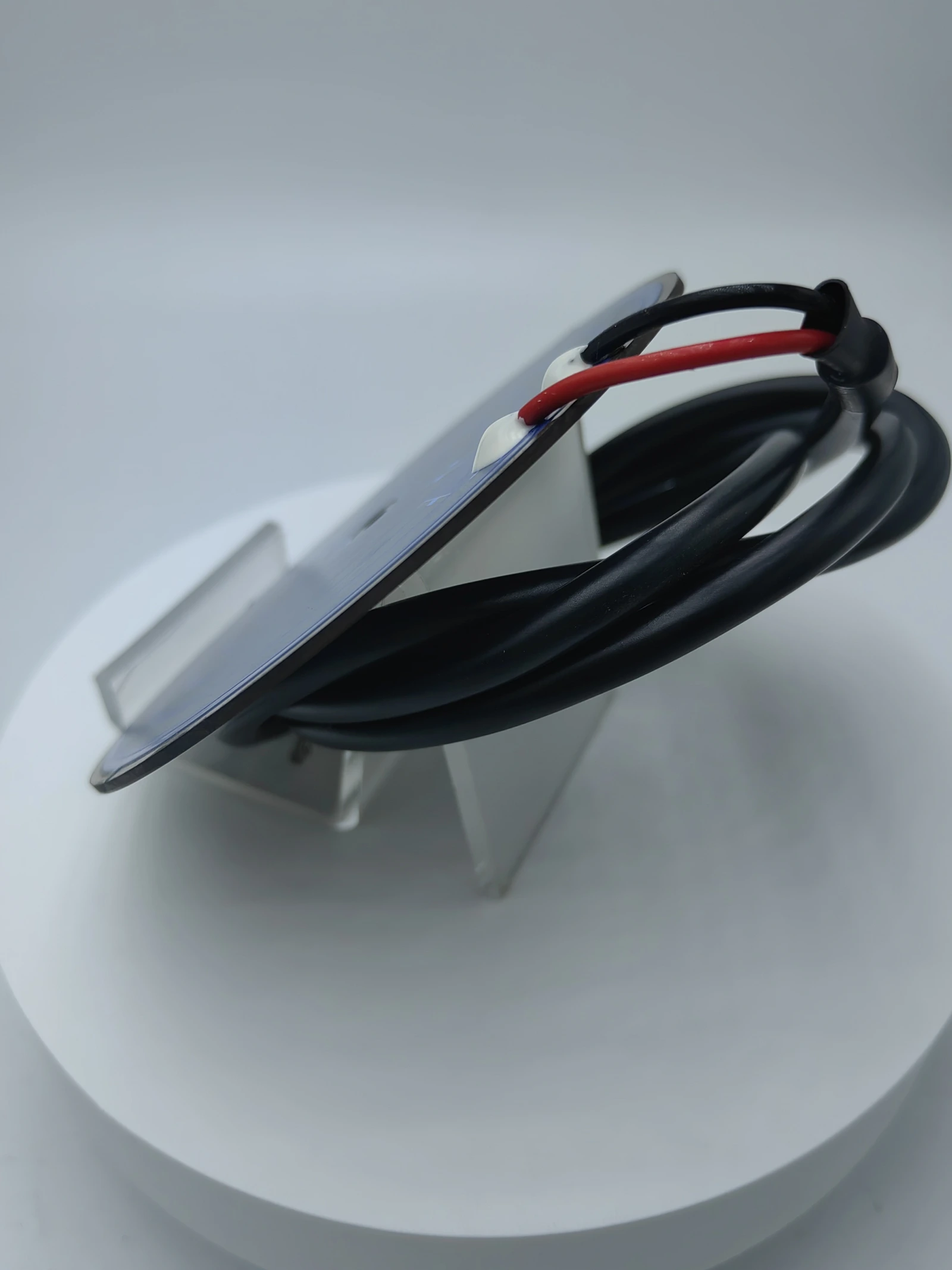The rear and edge of a circular heater assembly with insulated leads and terminal exits.