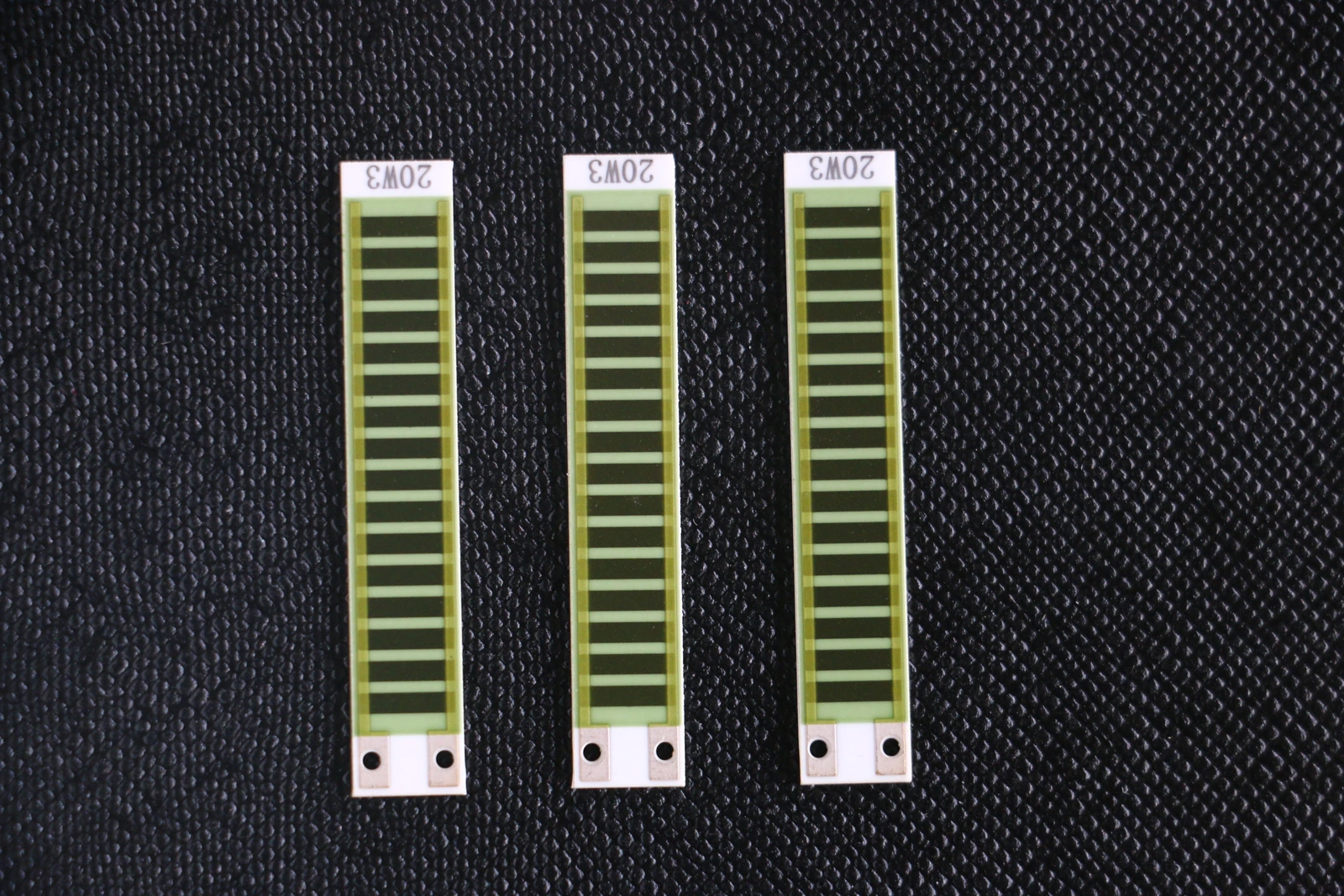 Three elongated ceramic resistor elements with repeated resistive sections and end connection holes.