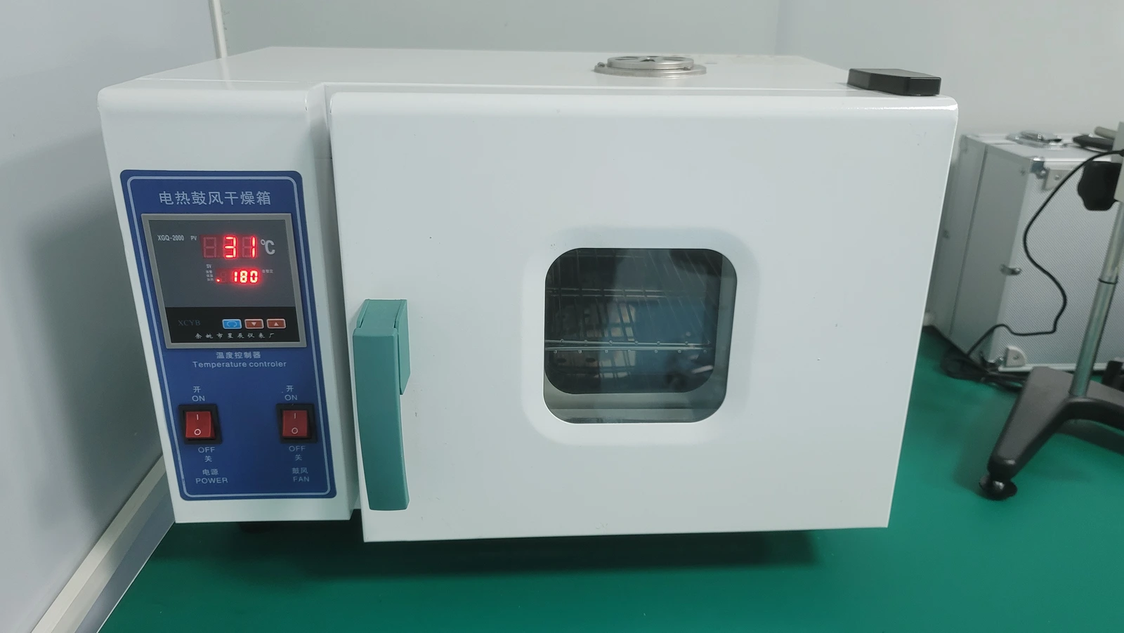 An oblique view of a laboratory oven showing its viewing window, door, handle and temperature controller.