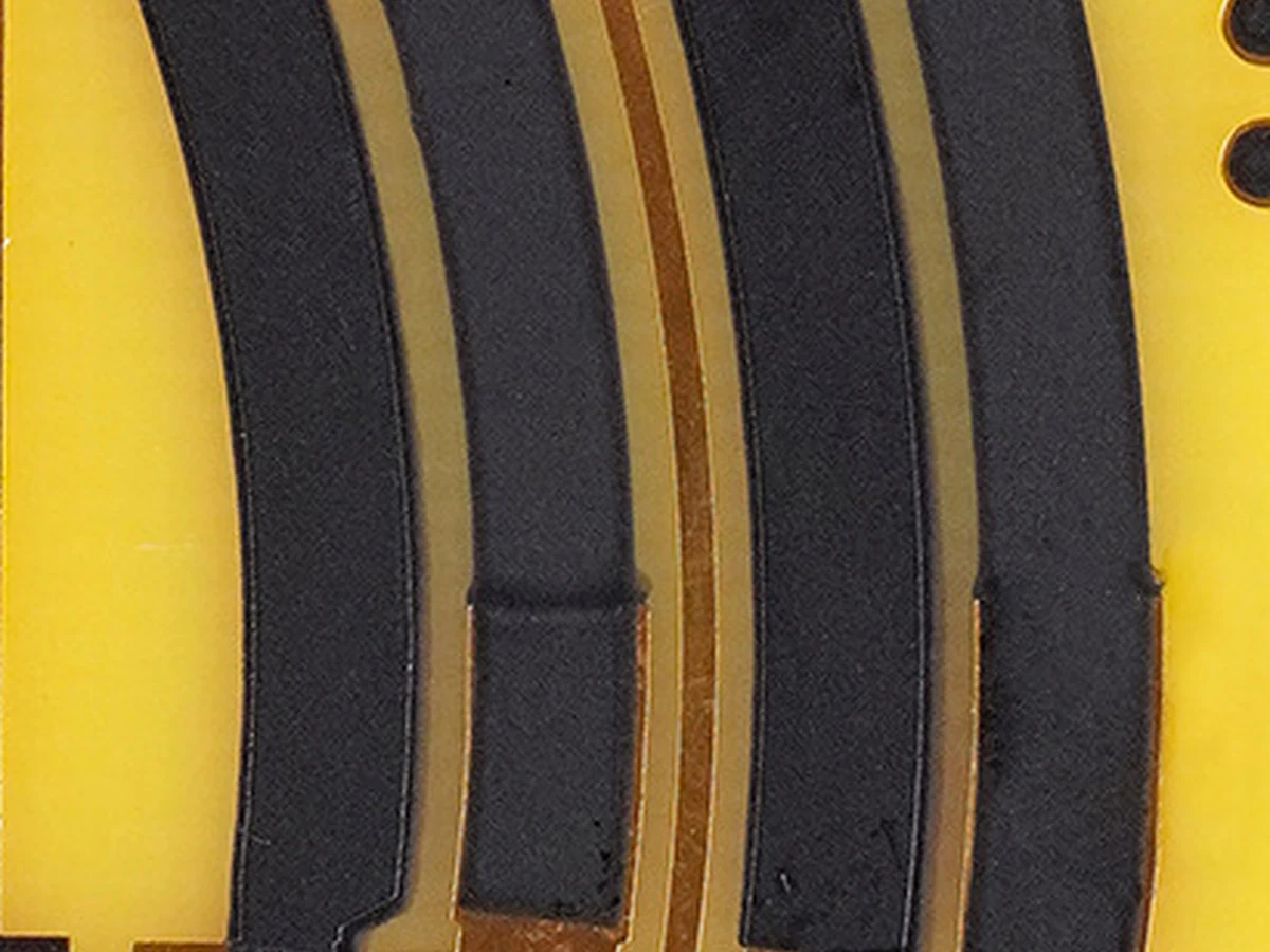 Source-derived macro view of black printed track texture and adjacent copper-colored conductor paths on the supplied board