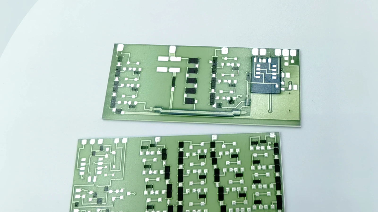 Real product photograph showing two rectangular circuit forms with different silver-colored routes, black blocks, and a localized blue area
