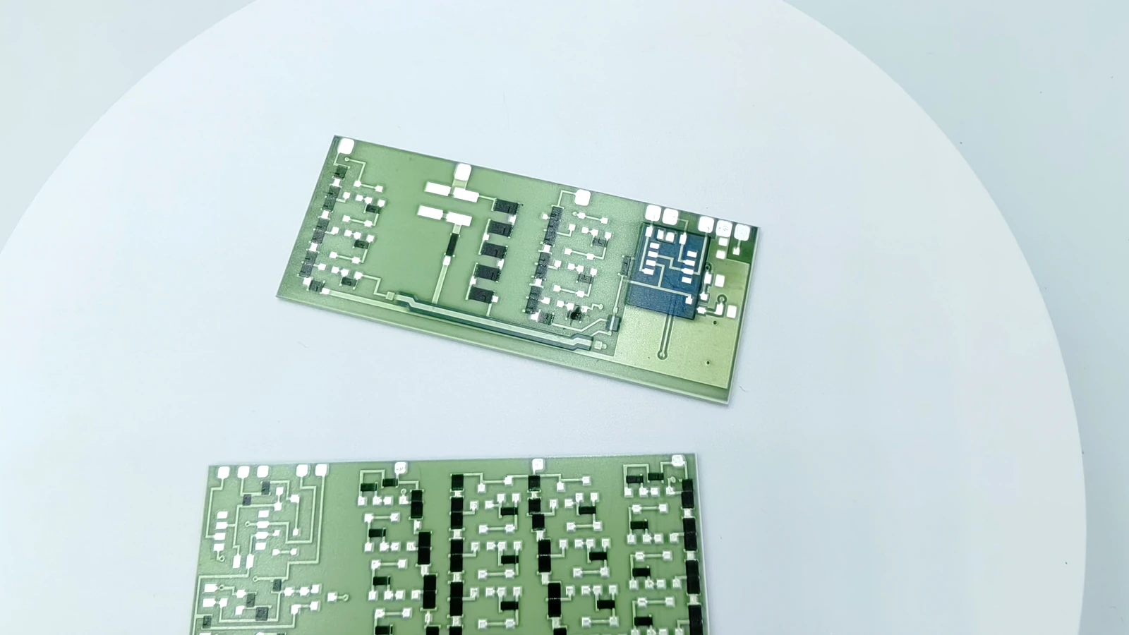 Real product photograph showing silver-colored routing, repeated black blocks, and rectangular green circuit forms