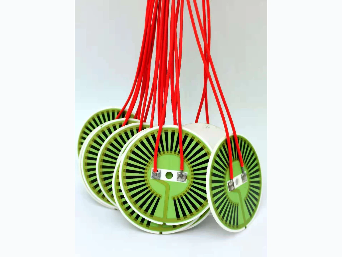 Round alumina heater discs showing white rims, visible printed patterns, terminals, and red leads