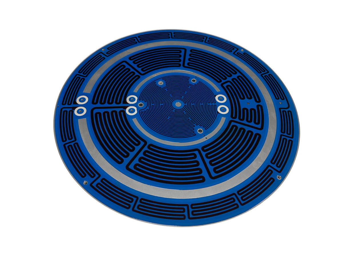 Circular aluminum substrate heater showing visible metal edge, printed surface, holes, and pads
