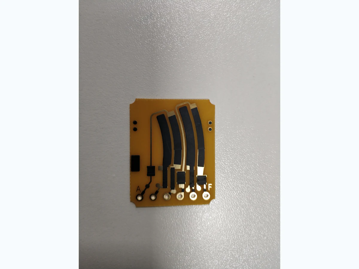 Carbon ink jumper PCB with several curved black printed paths, gold-colored pads, and terminal holes