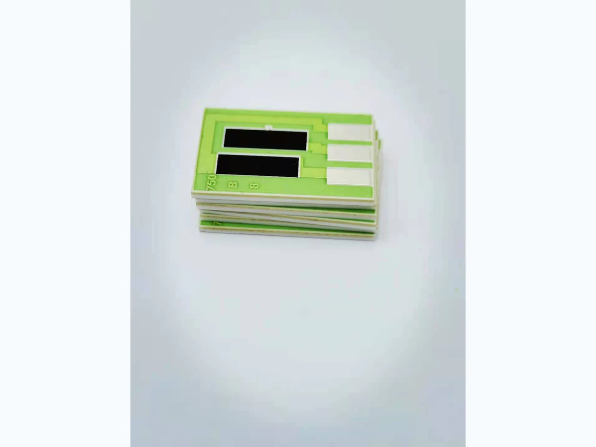 Stack of green ceramic thick film resistor substrates with black printed resistor blocks and silver-colored terminals