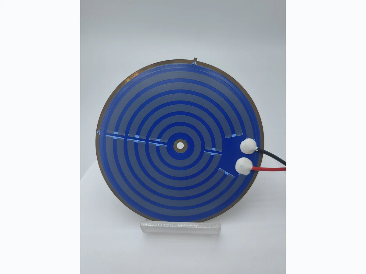 Round kettle heater plate showing the visible printed layout, metal edge, center opening, terminals, and leads