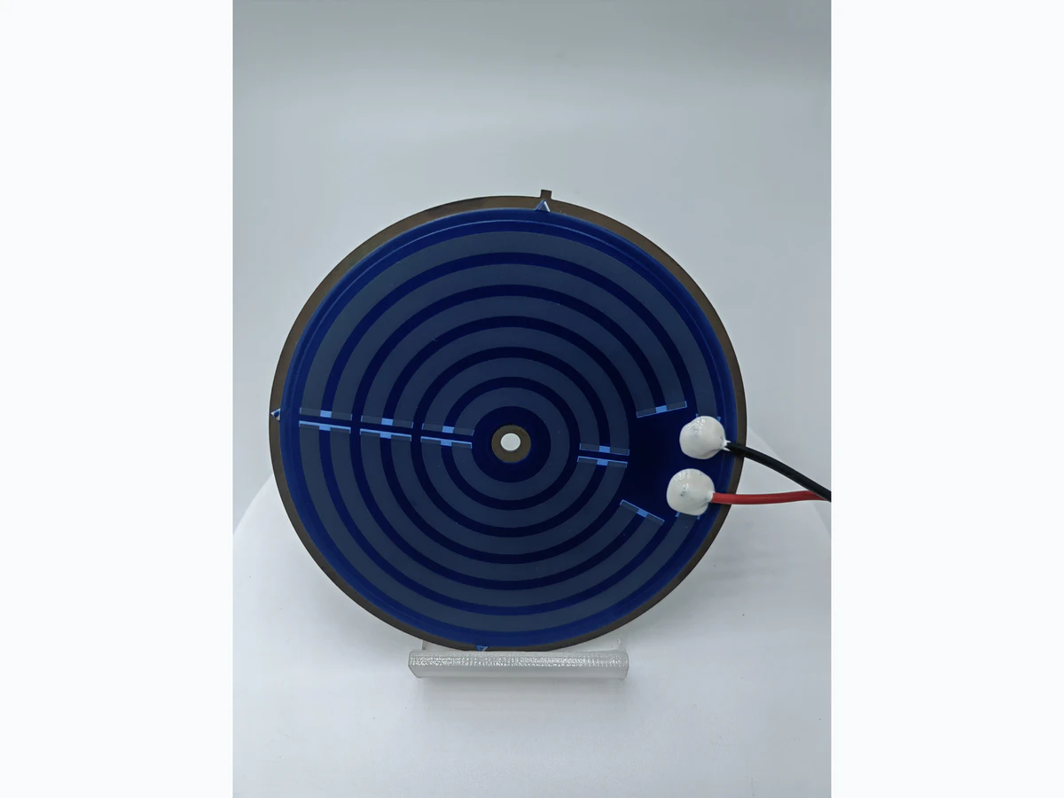 Supplied kettle heater photograph showing the first circular printed layout, terminal joints, red and black leads, and center feature