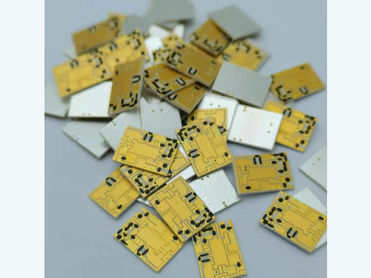 Verified batch detail of thick film filter circuits showing gold-colored patterned faces, dark functional areas, white ceramic bodies, and plain reverse-facing surfaces