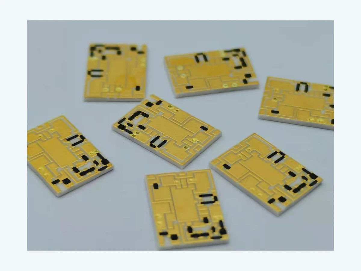 Group of rectangular thick film filter circuits with gold-colored surface patterns, dark functional areas, and white ceramic edges