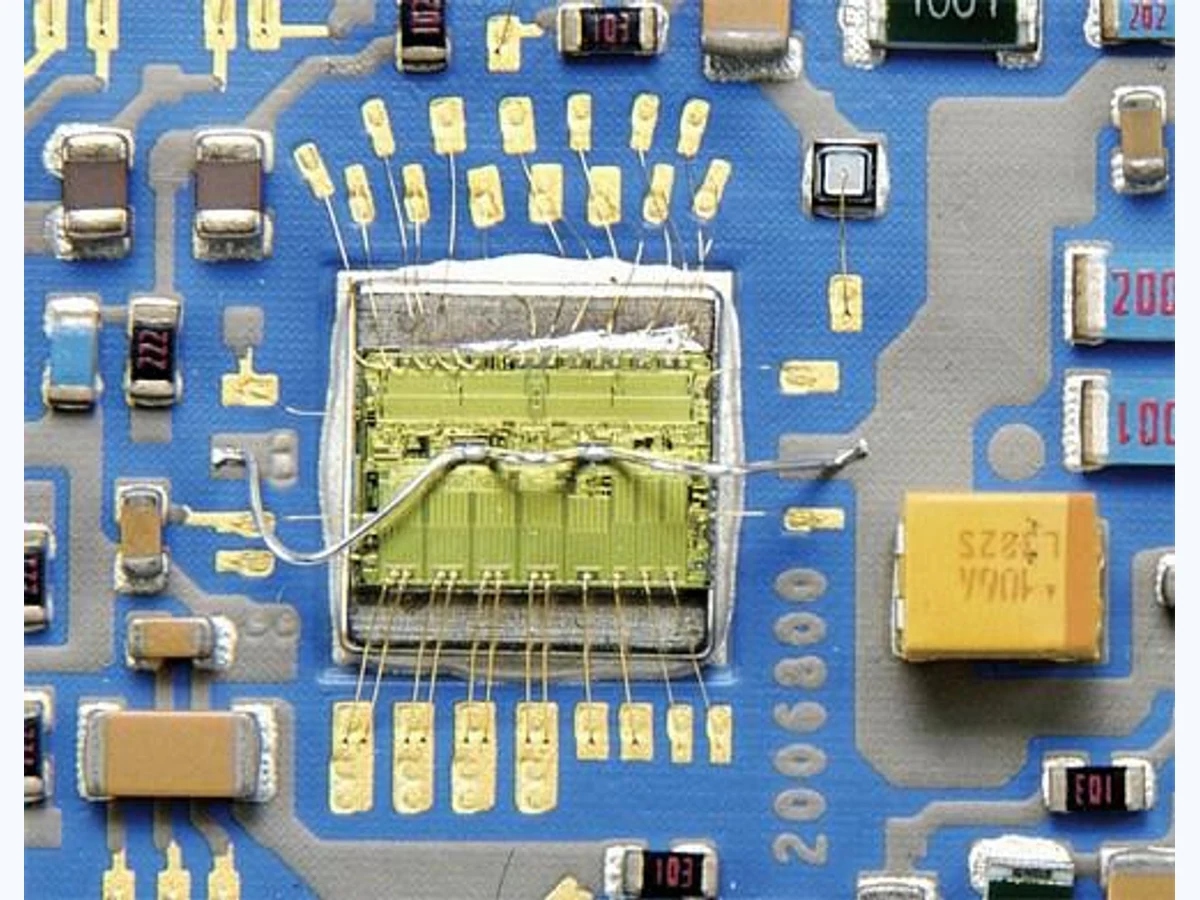 Supplied macro photograph showing a die area, fine wire bonds, printed routes, and mounted components on a hybrid circuit